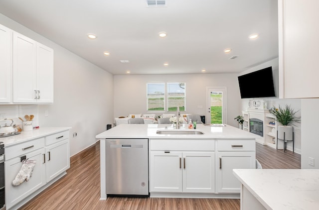 kitchen featuring stainless steel dishwasher, an island with sink, light wood-type flooring, white cabinetry, and a sink