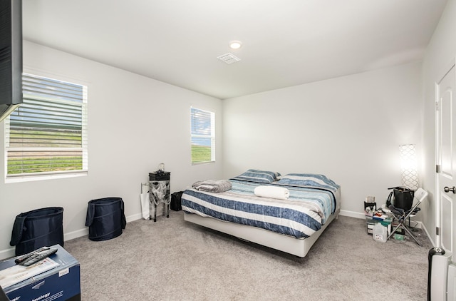 carpeted bedroom featuring baseboards, multiple windows, and visible vents