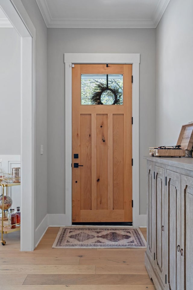entryway with ornamental molding, baseboards, and light wood finished floors
