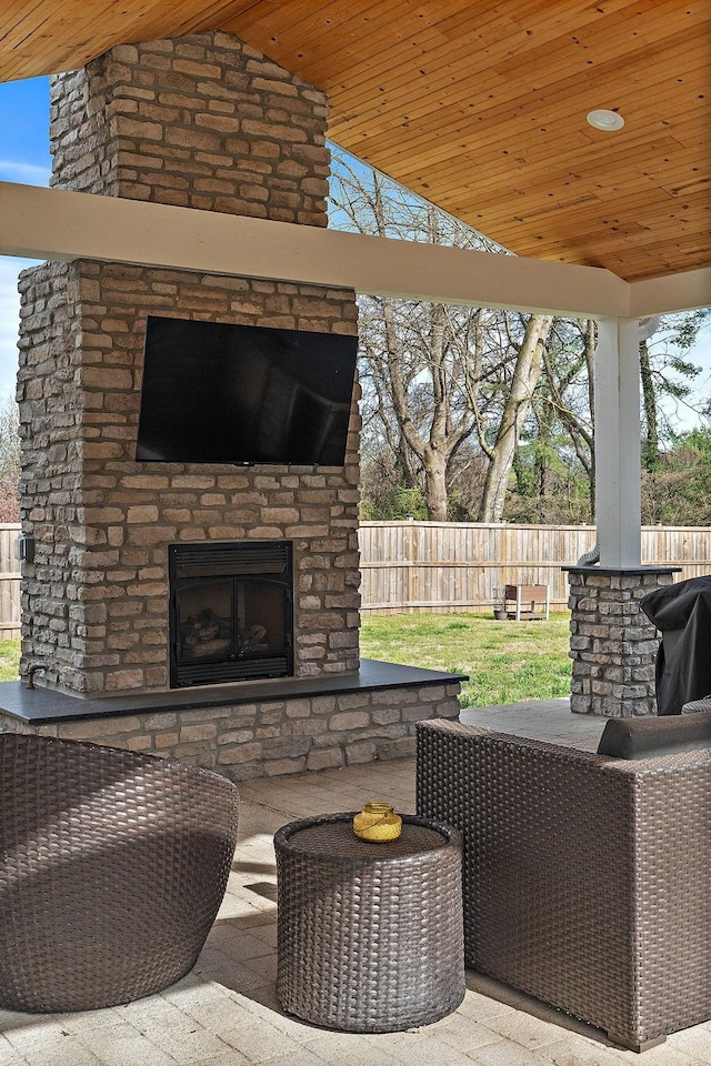 view of patio featuring grilling area, an outdoor living space with a fireplace, and fence