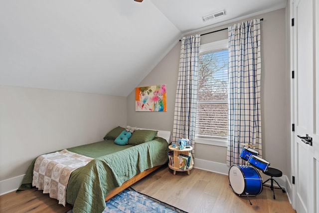 bedroom with wood finished floors, baseboards, lofted ceiling, and visible vents