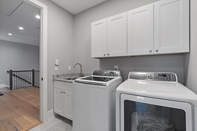 laundry area with recessed lighting, washing machine and dryer, light wood-style flooring, cabinet space, and a sink