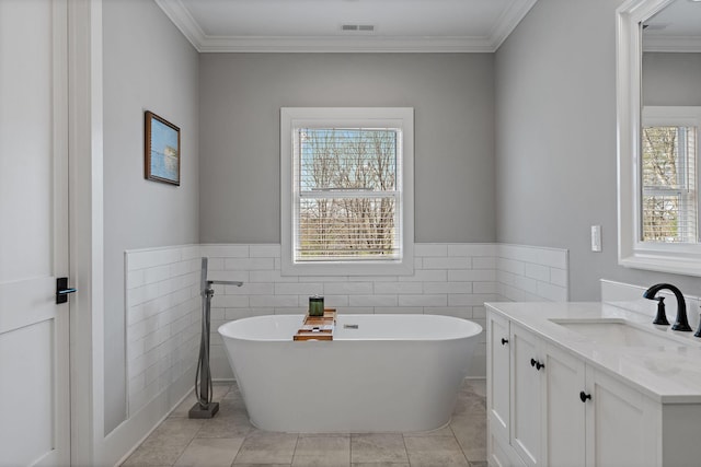 bathroom with tile walls, a soaking tub, visible vents, and a wealth of natural light