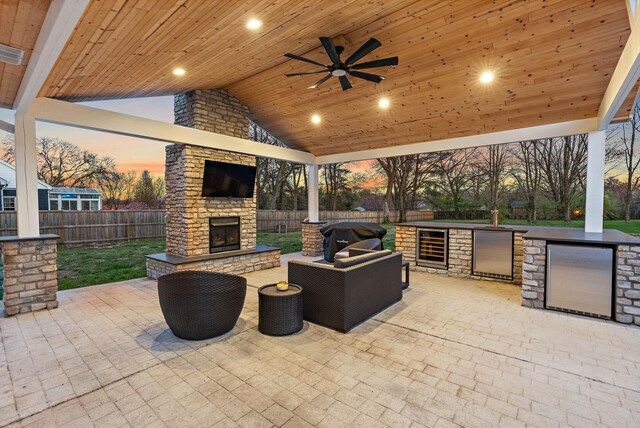 view of patio featuring grilling area, area for grilling, a fenced backyard, ceiling fan, and an outdoor living space with a fireplace