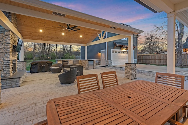 patio terrace at dusk with visible vents, ceiling fan, a garage, outdoor dining space, and fence
