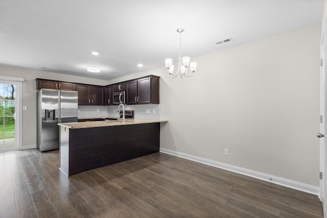kitchen featuring tasteful backsplash, a notable chandelier, dark wood-style floors, dark brown cabinets, and appliances with stainless steel finishes