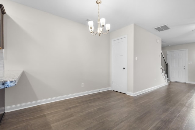 spare room with visible vents, baseboards, a chandelier, dark wood finished floors, and stairs