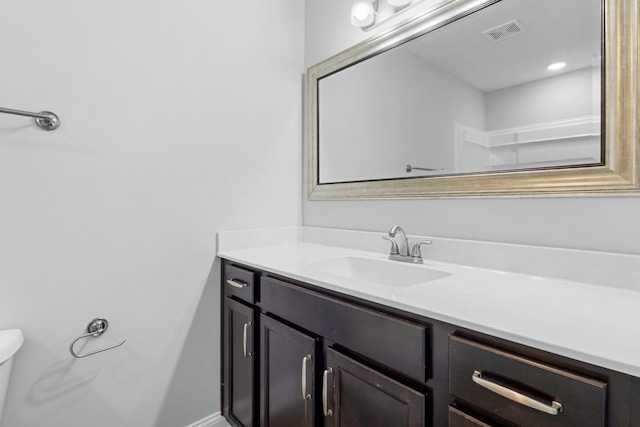 bathroom with toilet, vanity, and visible vents
