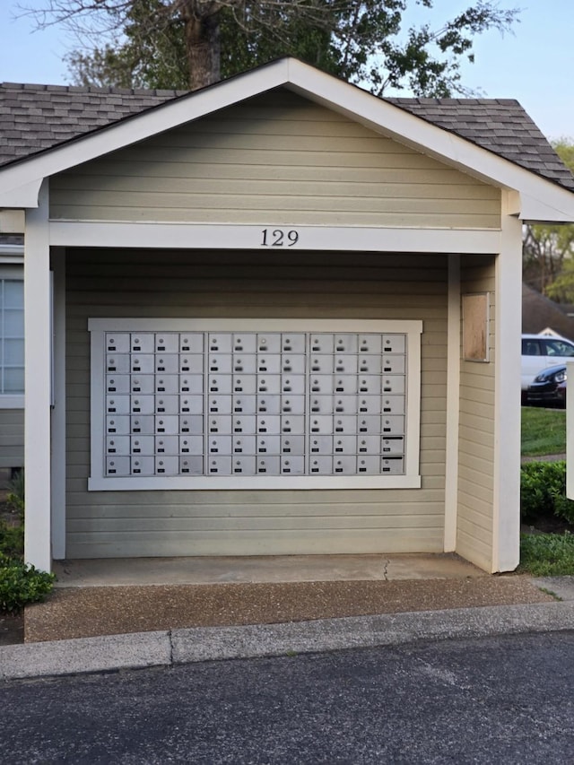 view of home's exterior with roof with shingles, mail area, and a garage