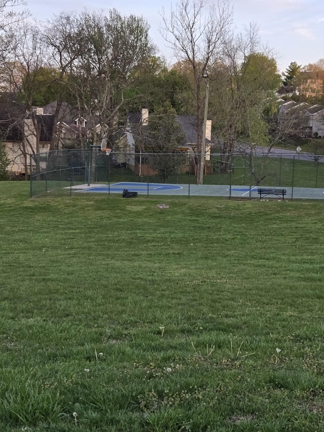 view of property's community with fence, a lawn, and community basketball court