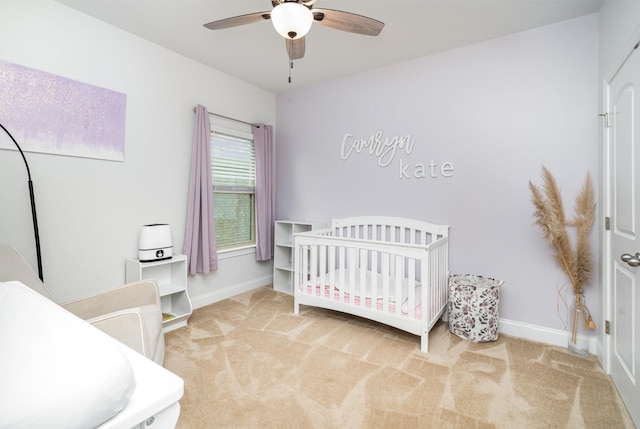 bedroom with a crib, ceiling fan, baseboards, and carpet floors