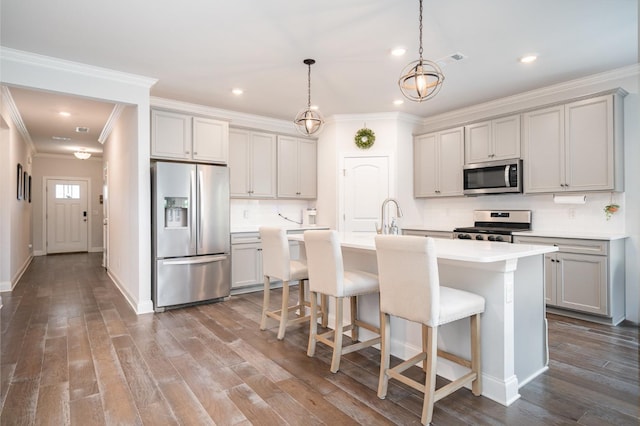 kitchen featuring tasteful backsplash, ornamental molding, appliances with stainless steel finishes, and an island with sink
