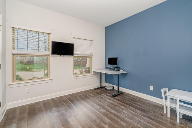 unfurnished office featuring plenty of natural light, baseboards, and wood finished floors