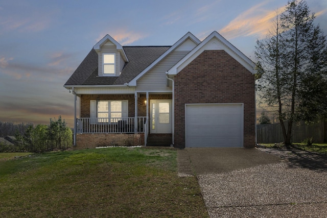 view of front of house with a front yard, a porch, fence, brick siding, and driveway