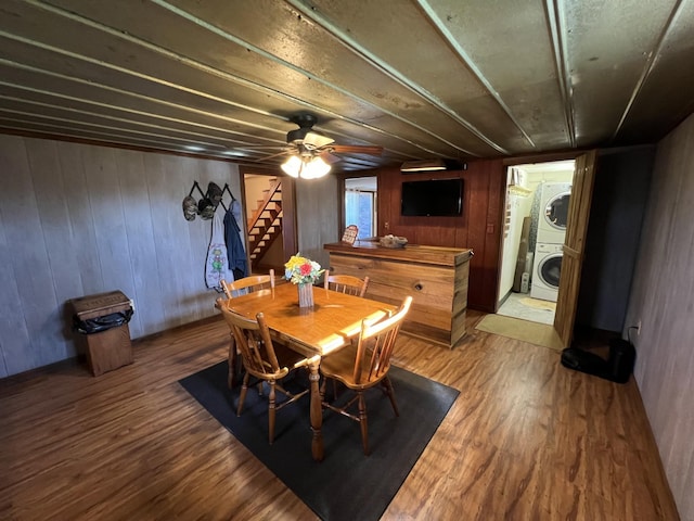 dining area featuring estacked washer and dryer, stairs, light wood-type flooring, and wood walls