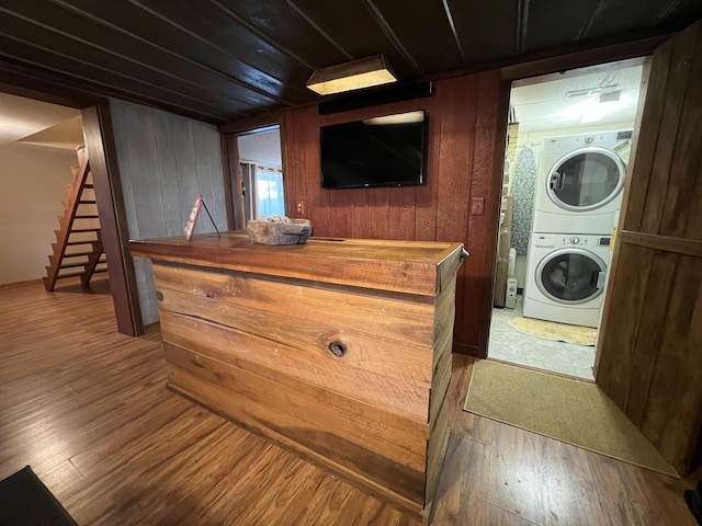 laundry area featuring estacked washer and dryer, wood finished floors, and wood walls