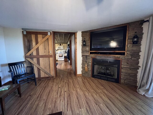 unfurnished living room with wood finished floors, a stone fireplace, and baseboards