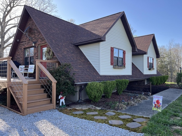 view of front of house featuring roof with shingles, a wooden deck, and brick siding