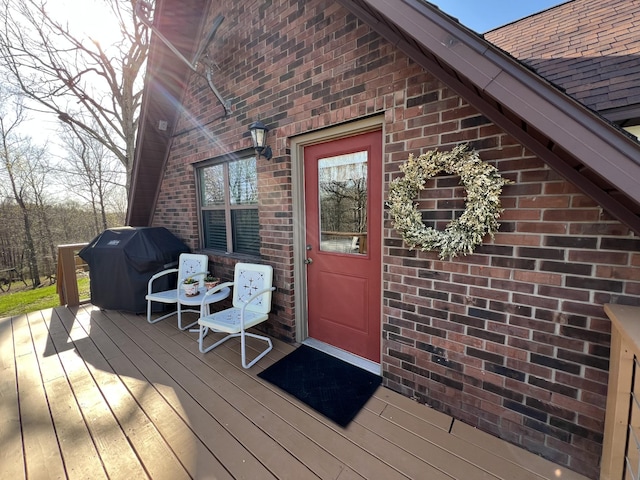 entrance to property featuring brick siding and a wooden deck
