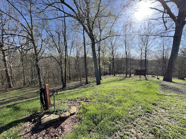 view of green lawn featuring a wooded view