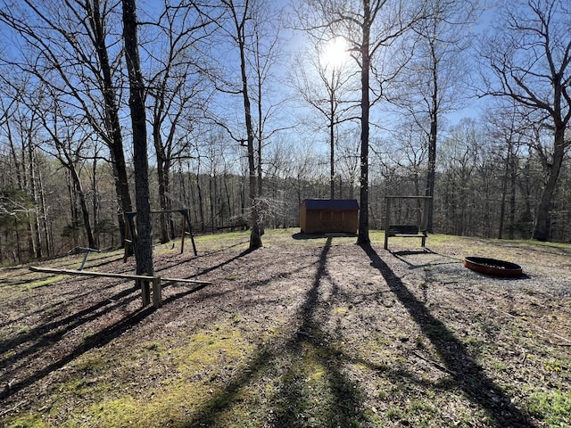view of yard featuring a storage unit, an outdoor structure, and a wooded view