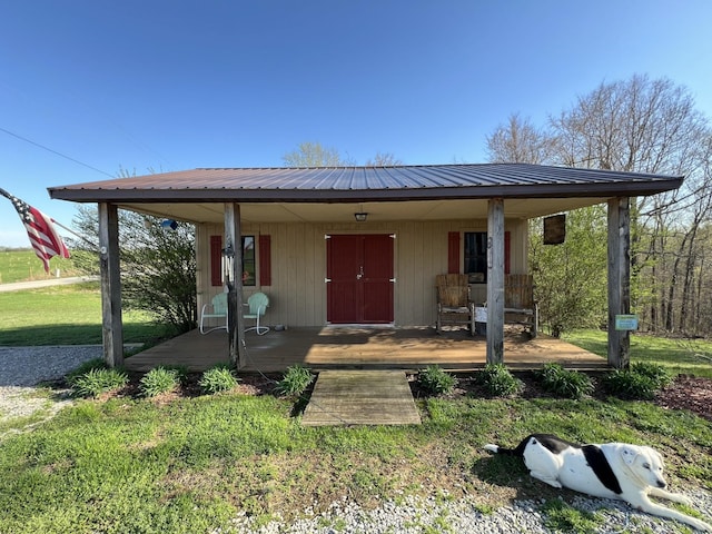 view of front of house featuring covered porch, metal roof, and a front lawn