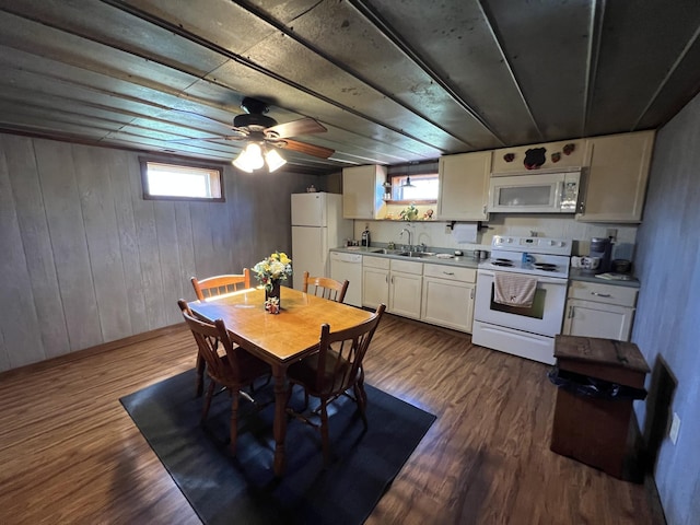 dining room with plenty of natural light, dark wood finished floors, ceiling fan, and wood walls