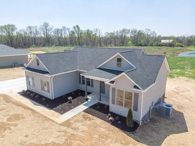 view of front of home with central air condition unit and roof with shingles