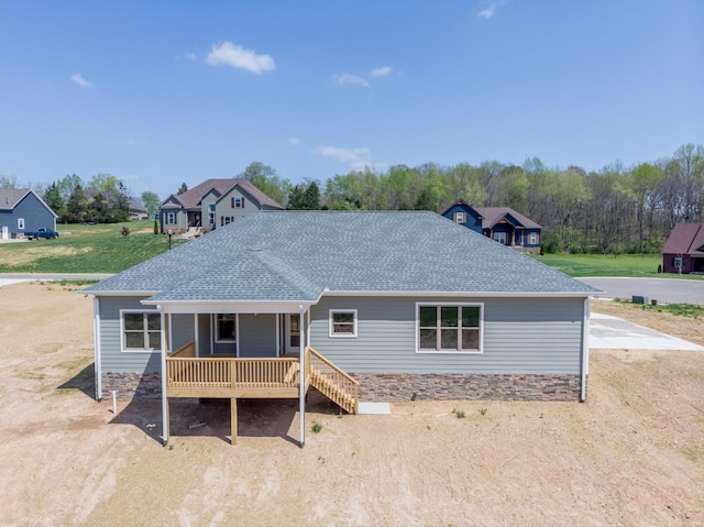rear view of property with covered porch and roof with shingles