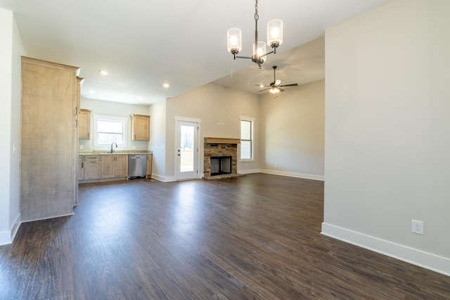 unfurnished living room with a sink, baseboards, and ceiling fan with notable chandelier