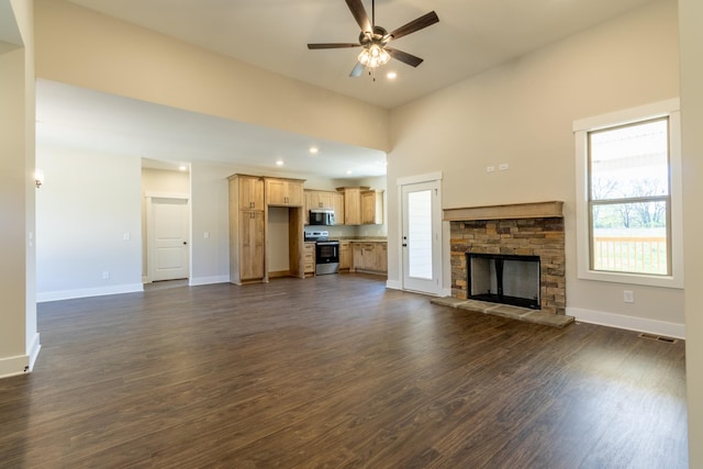 unfurnished living room featuring baseboards, a fireplace, a ceiling fan, visible vents, and dark wood finished floors