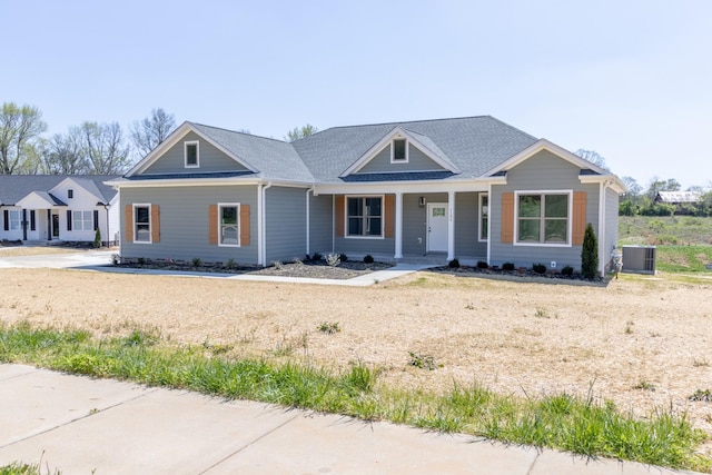 view of front of property featuring a shingled roof, cooling unit, and covered porch