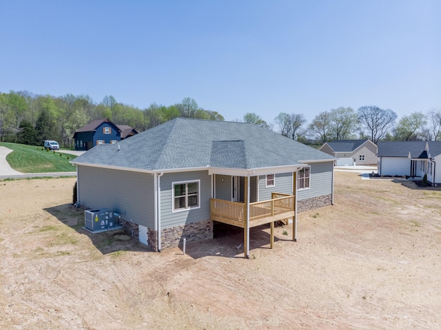 rear view of property with a shingled roof and a wooden deck