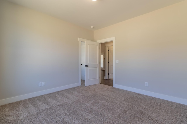 carpeted empty room featuring baseboards