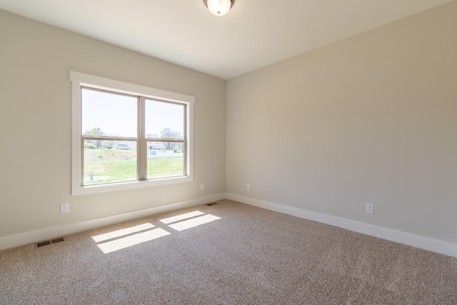 carpeted spare room with visible vents and baseboards