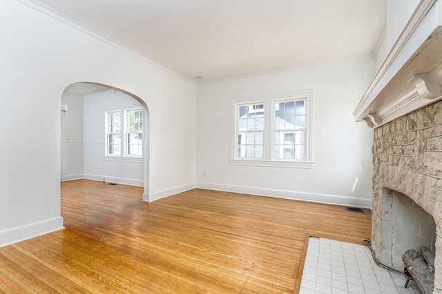 906 Myers Ave, Columbia, TN 38401 - unfurnished living room featuring a fireplace with flush hearth, arched walkways, light wood-type flooring, baseboards, and crown molding