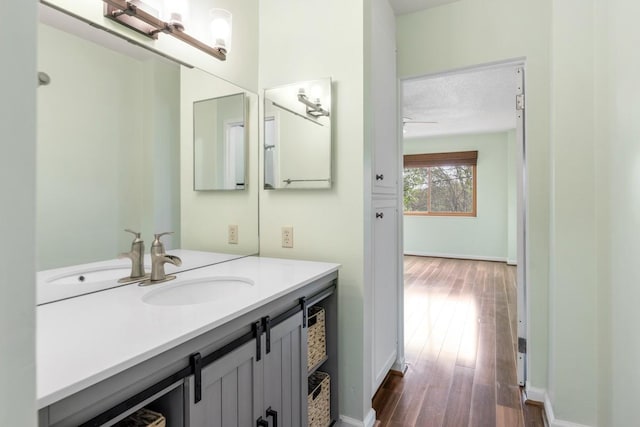 bathroom featuring baseboards, a ceiling fan, vanity, and wood finished floors