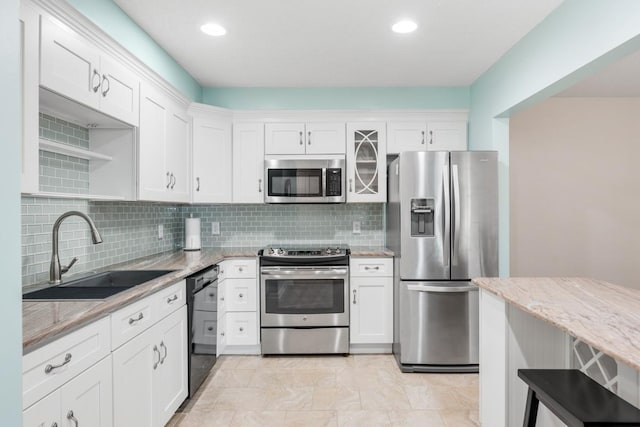 kitchen featuring open shelves, white cabinets, light stone countertops, appliances with stainless steel finishes, and a sink