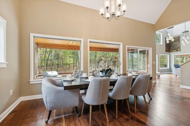 dining space with dark wood-type flooring, high vaulted ceiling, an inviting chandelier, and baseboards