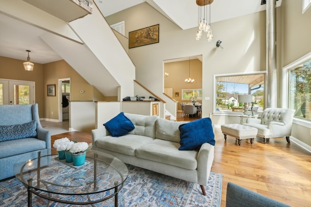 living room featuring a towering ceiling, visible vents, wood finished floors, stairs, and a notable chandelier