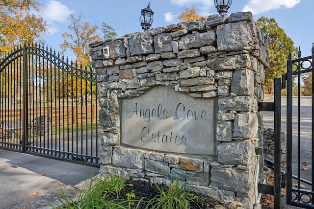 community / neighborhood sign featuring fence and a gate