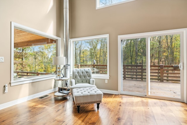 sitting room with a towering ceiling, visible vents, baseboards, and hardwood / wood-style floors