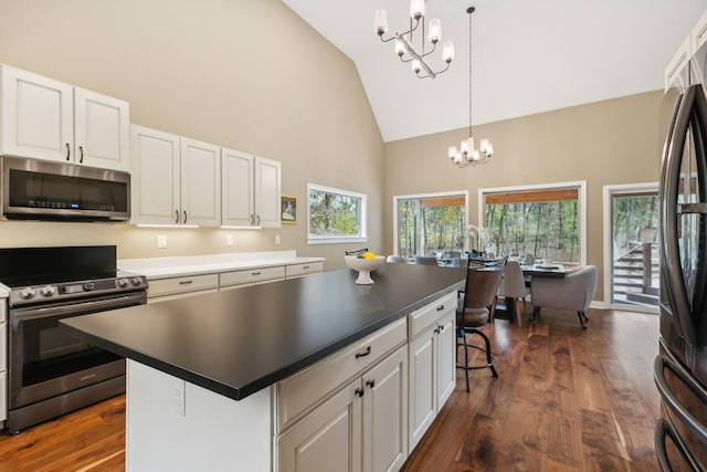 kitchen with stainless steel appliances, dark wood-style floors, white cabinetry, and a chandelier