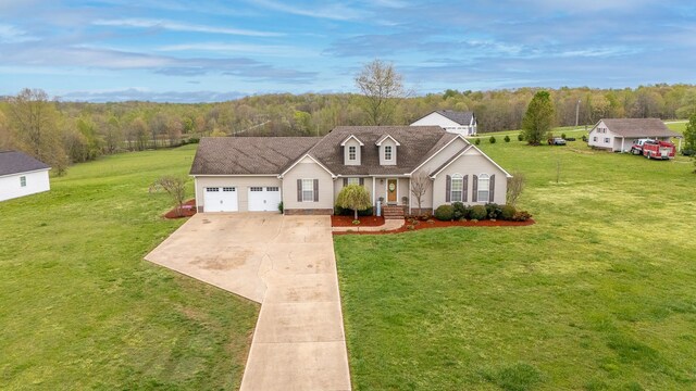 cape cod home with a garage, roof with shingles, a front lawn, a wooded view, and concrete driveway
