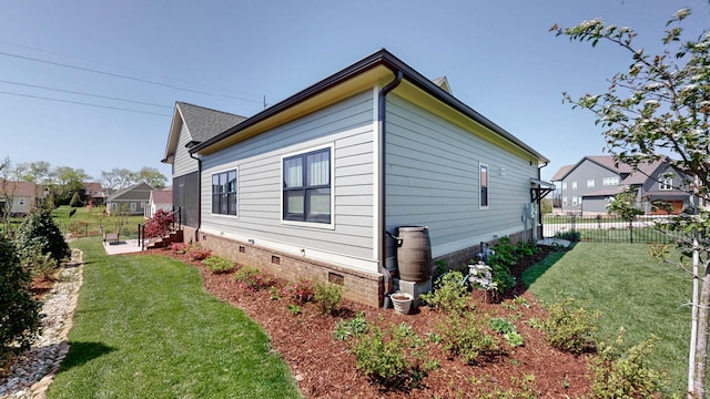 view of side of home with fence and a lawn