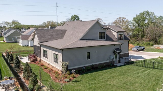 view of side of property with a shingled roof, crawl space, fence, and a lawn