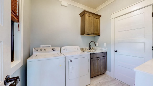washroom with separate washer and dryer, a sink, ornamental molding, and cabinet space