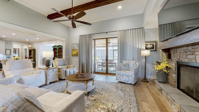 living area featuring a ceiling fan, a stone fireplace, recessed lighting, wood finished floors, and beam ceiling