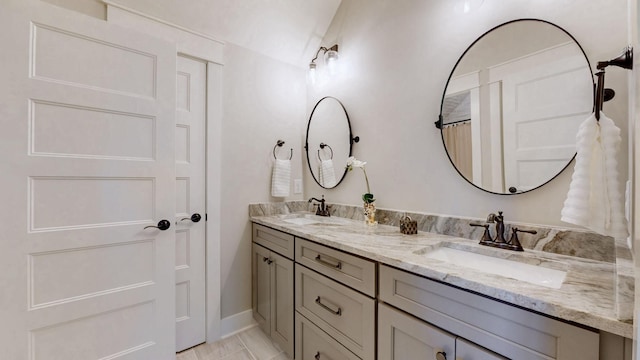 bathroom with a sink, baseboards, and double vanity