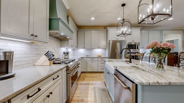 kitchen with custom range hood, a chandelier, recessed lighting, appliances with stainless steel finishes, and a sink
